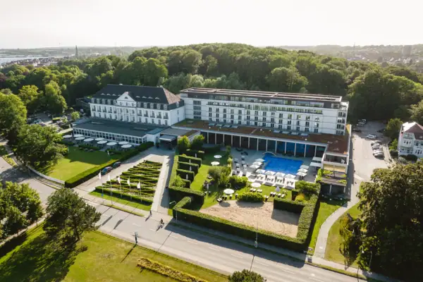 Ein großes weißes Gebäude mit einem Pool und Bäumen.