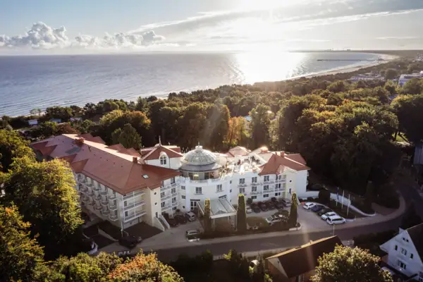 Un grande edificio con alberi e uno specchio d'acqua.