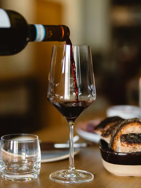 Una persona versa il vino in un bicchiere.