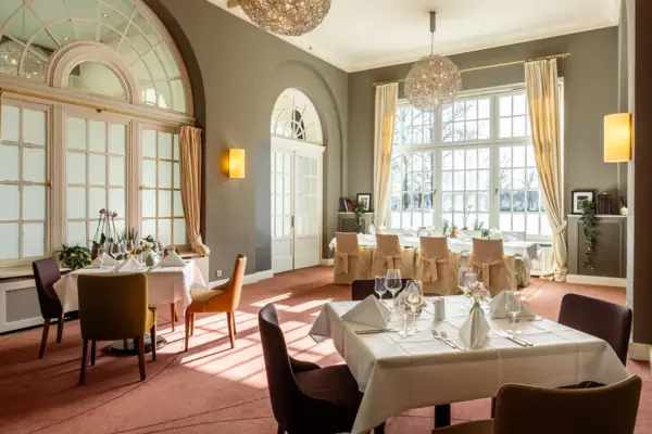 Una sala con tavoli e sedie all’A-ROSA Travemünde.