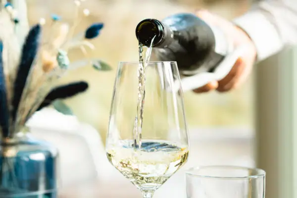 Weinservice Eine Person gießt Wein in ein Glas.