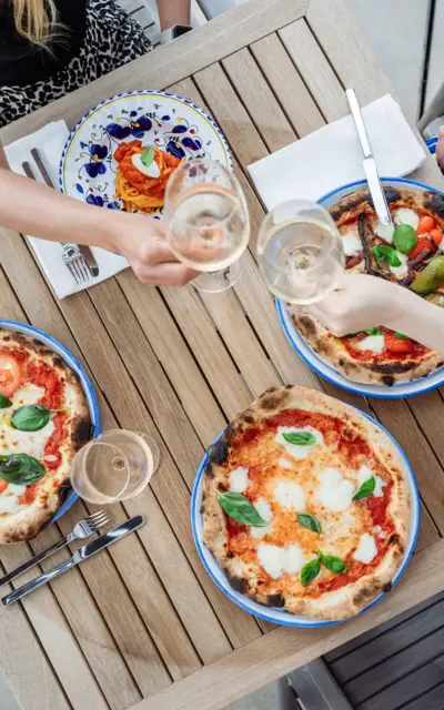 Gruppo di persone che mangiano pizze su un tavolo.