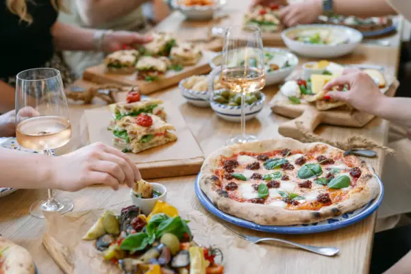 Gruppo di persone che mangiano pizze su un tavolo.