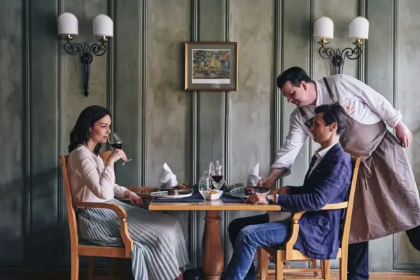 Ein Mann bedient eine Frau an einem Tisch.