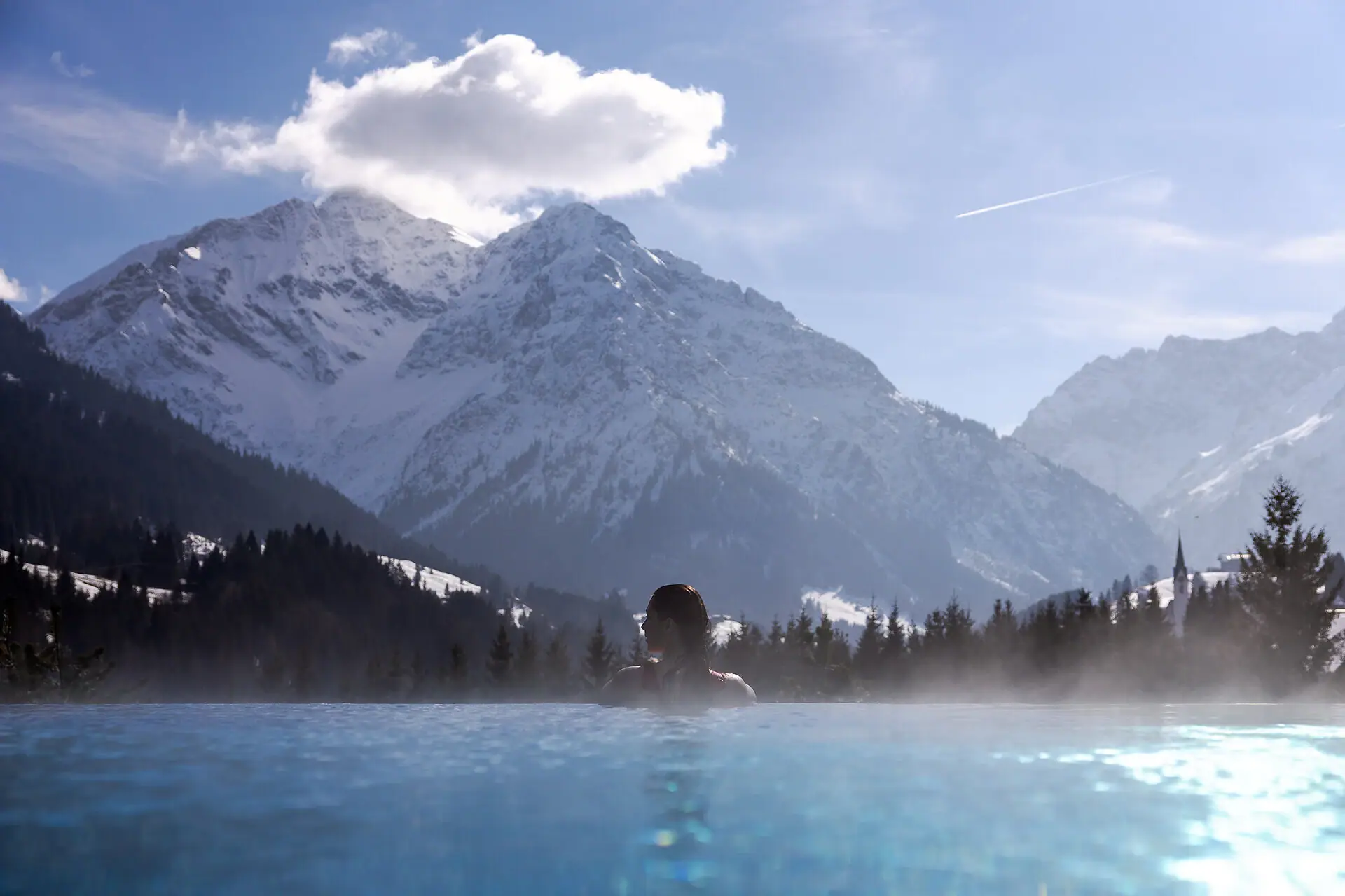 Persona in piscina con montagne sullo sfondo.
