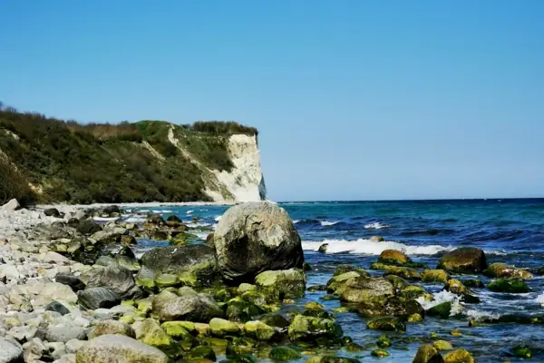 Felsige Küste mit Wasser und Klippen im Hintergrund.
