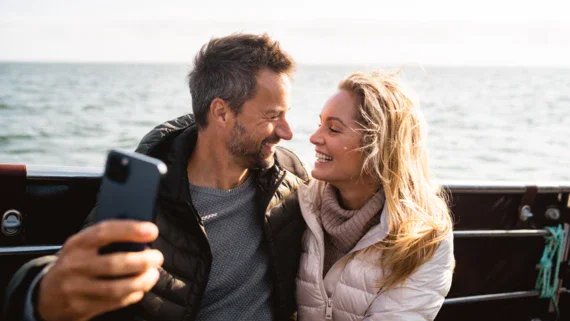 Uomo e donna si scattano un selfie all'aperto con uno sfondo di lago.