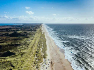 Lunga spiaggia con onde che si infrangono sulla riva.