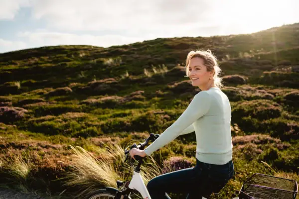 Una donna va in bicicletta tra le dune di Sylt.