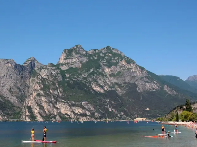 Persone su tavole da stand up paddle su un lago circondato da montagne.