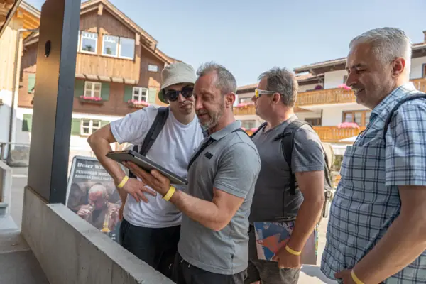 Un gruppo di uomini è in piedi all'esterno e guarda un tablet.