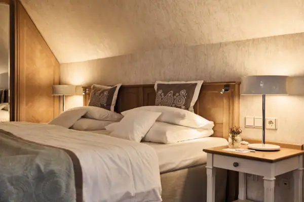 Bett mit Kissen und Nachttischlampen in einem stilvoll eingerichteten Schlafzimmer.