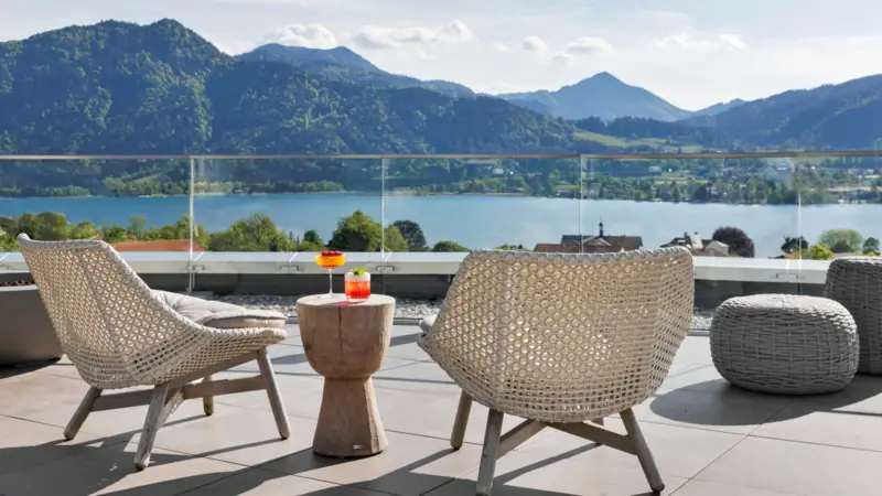 Ein Tisch und Stühle auf einer Terrasse mit Blick auf ein Gewässer.
