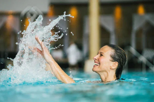 Donna che nuota in piscina con schizzi d'acqua.