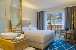 Zona notte con bagno open space Camera da letto con grande letto, sedia e grande specchio.