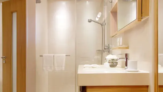 Un bagno luminoso con doccia e lavabo.