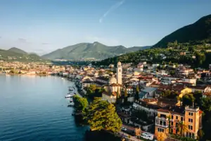 Stadt am Wasser mit Bergen im Hintergrund und Häusern am Ufer.