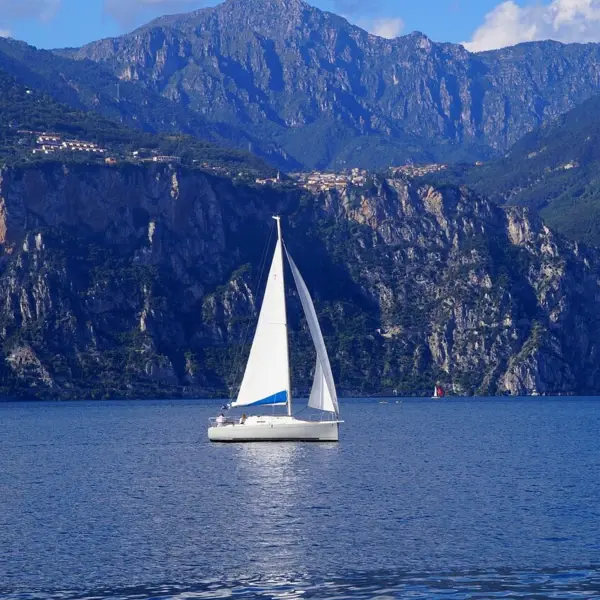 Barca a vela sull'acqua con montagne sullo sfondo.