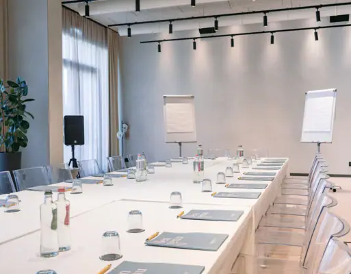 Una sala conferenze con tavoli bianchi e sedie.