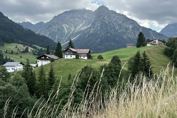Ein Haus auf einem Hügel mit Bäumen und Bergen im Hintergrund.