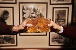 Due mani reggono dei bicchieri da cui fuoriesce del liquido.