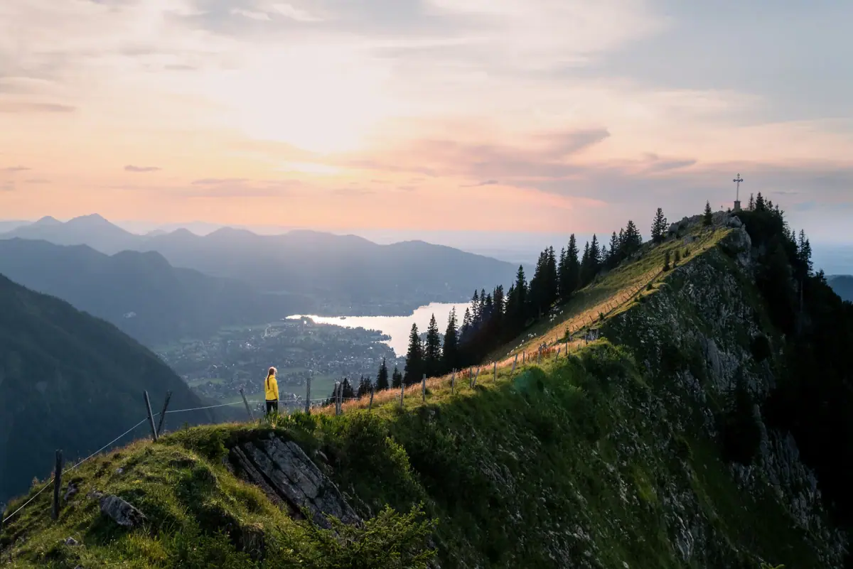 Una persona si trova sulla cima di una montagna durante un'escursione sul lago Tegernsee.