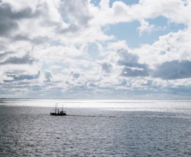 Barca che naviga nell'oceano con cielo nuvoloso.