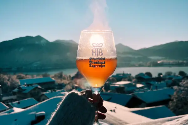 Tegernsee d'inverno Una mano regge un bicchiere di vino da cui sale del vapore.