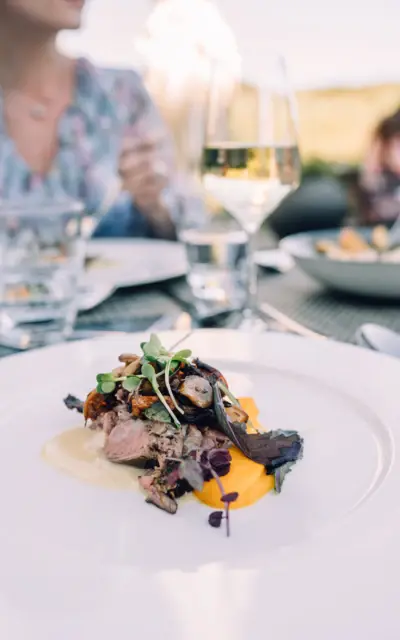 Piatto di cibo gourmet servito su un tavolo con calice di vino.