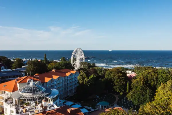Das A-ROSA Strandidyll Heringsdorf neben einem Riesenrad und der Ostsee dahinter.