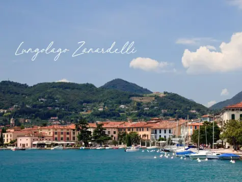 Un lago con edifici circostanti e diverse barche sull'acqua.