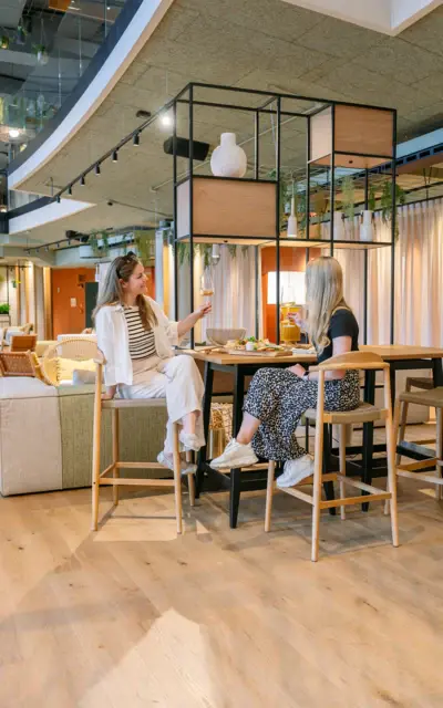 Due donne sedute a un tavolo in un ambiente interno.