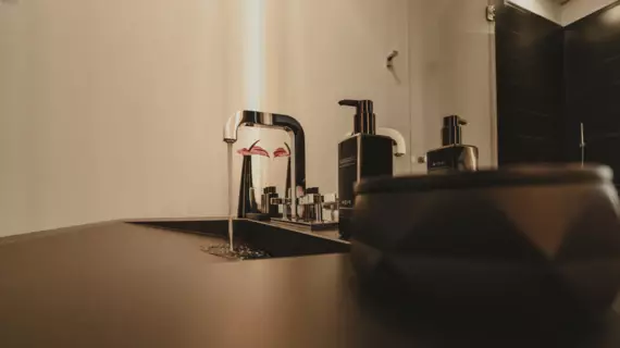 Un elegante lavabo nero con un rubinetto d'argento da cui sgorga l'acqua. 