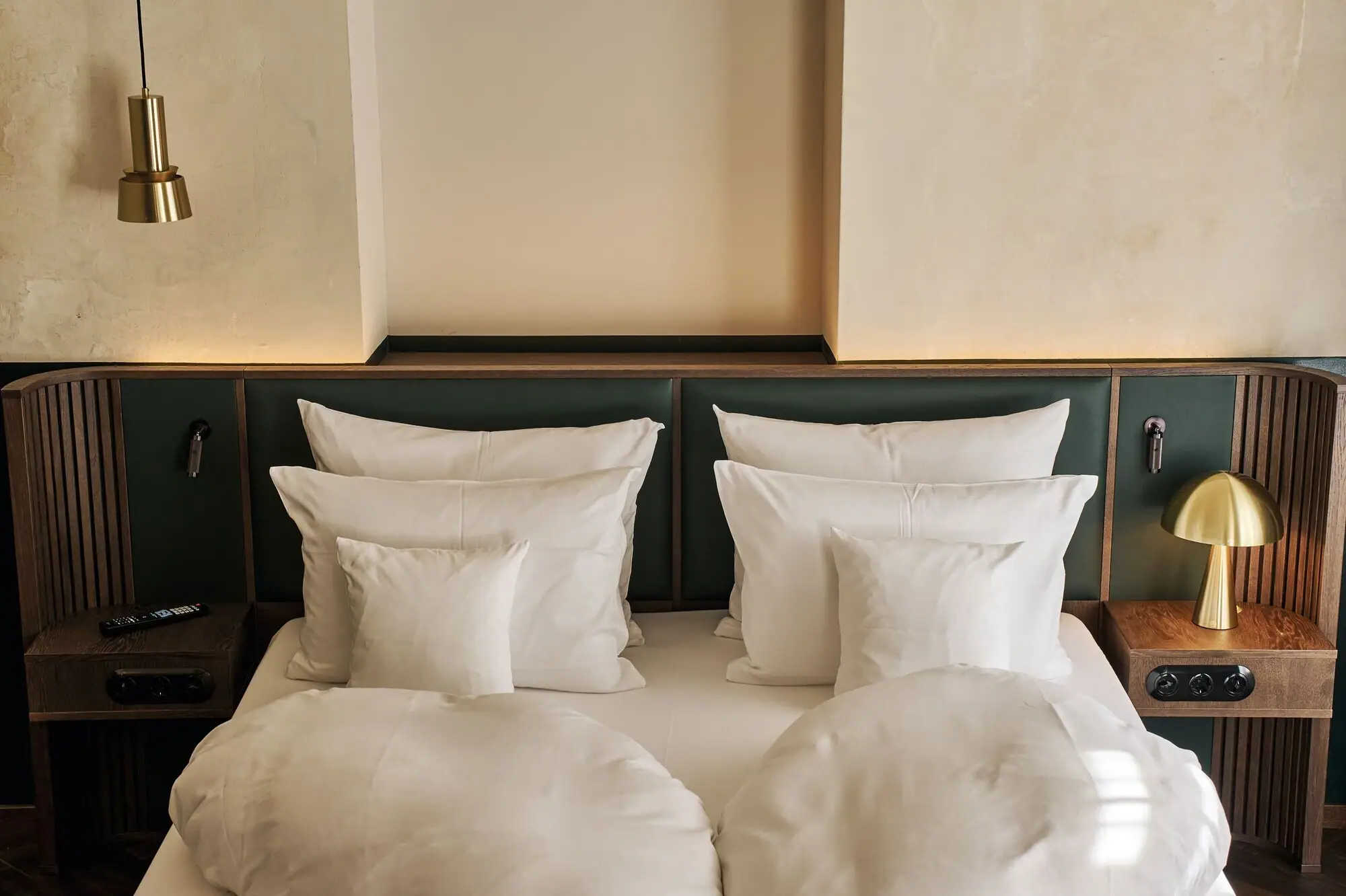 Letto con cuscini bianchi e testiera verde.
