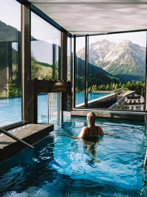 Una donna in una piscina con le montagne sullo sfondo.