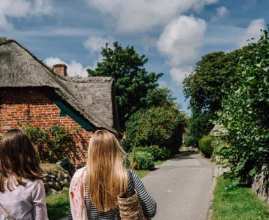 Due donne camminano lungo una strada in un ambiente esterno.