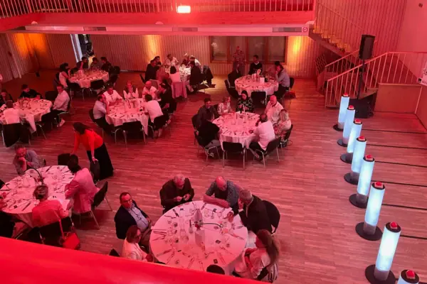 Gruppo di persone sedute ai tavoli in una stanza con luce rossa