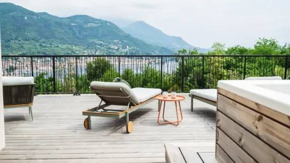 Terrazza esterna con tavolo e sedie, con vista su montagne.