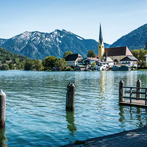 Un lago con una chiesa e le montagne sullo sfondo.