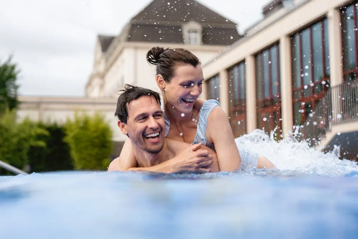 Un uomo porta in braccio una donna in una piscina.