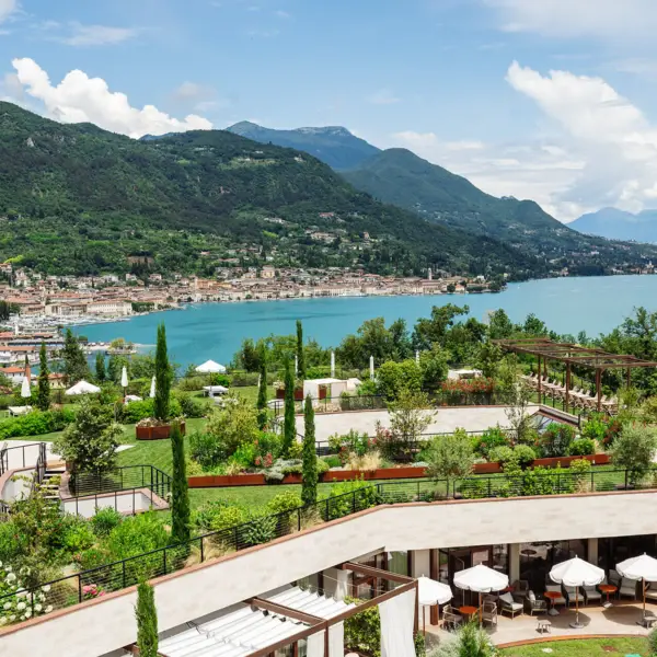 L'A-ROSA con giardino e il Lago di Garda sullo sfondo delle montagne.