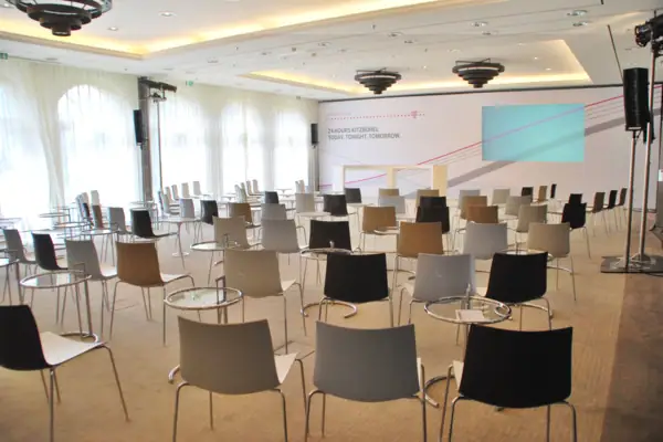 Ein Raum mit vielen Stühlen und einer Projektorleinwand.