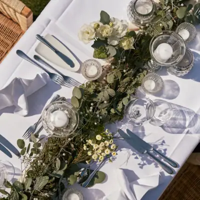 Ein Tisch mit weißer Tischdecke, Kerzen und Blumen.