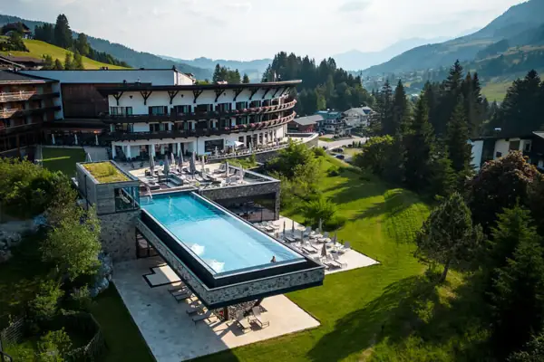 Ein Außenpool in einem Hotel mit Bäumen und klarem Himmel im Hintergrund.