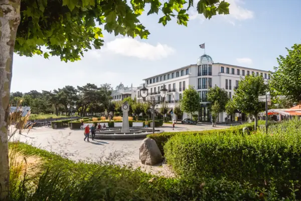 Weißes Gebäude mit einem schneebedeckten Tannenbaum davor.
