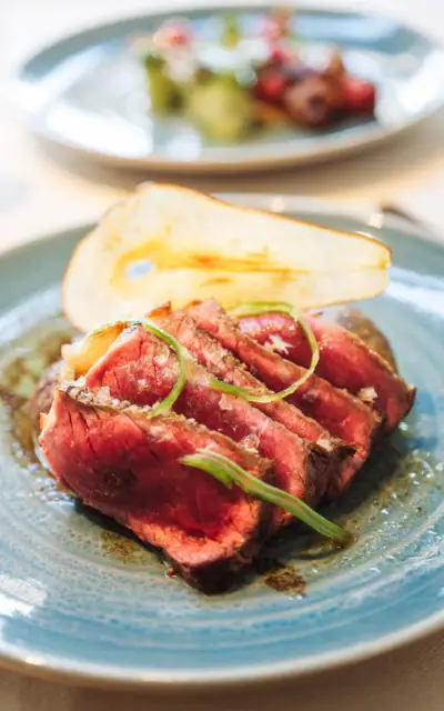 Piatto di carne rossa con guarnizione su un tavolo.