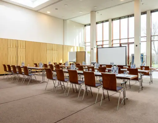 Una sala con tavoli e sedie all’A-ROSA Travemünde.