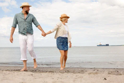 Uomo e donna che si tengono per mano su una spiaggia.