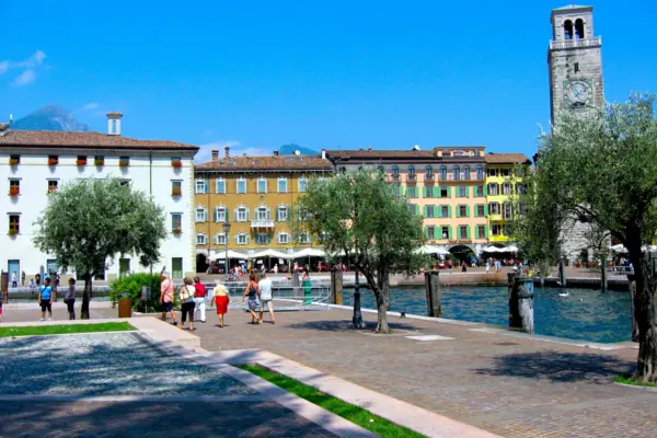 Riva del Garda Un gruppo di persone passeggia lungo un sentiero vicino all'acqua.