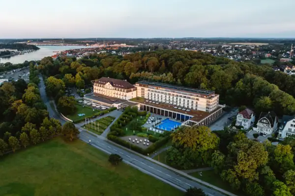 Das A-ROSA Travemünde mit Pool, umgeben von Bäumen.
